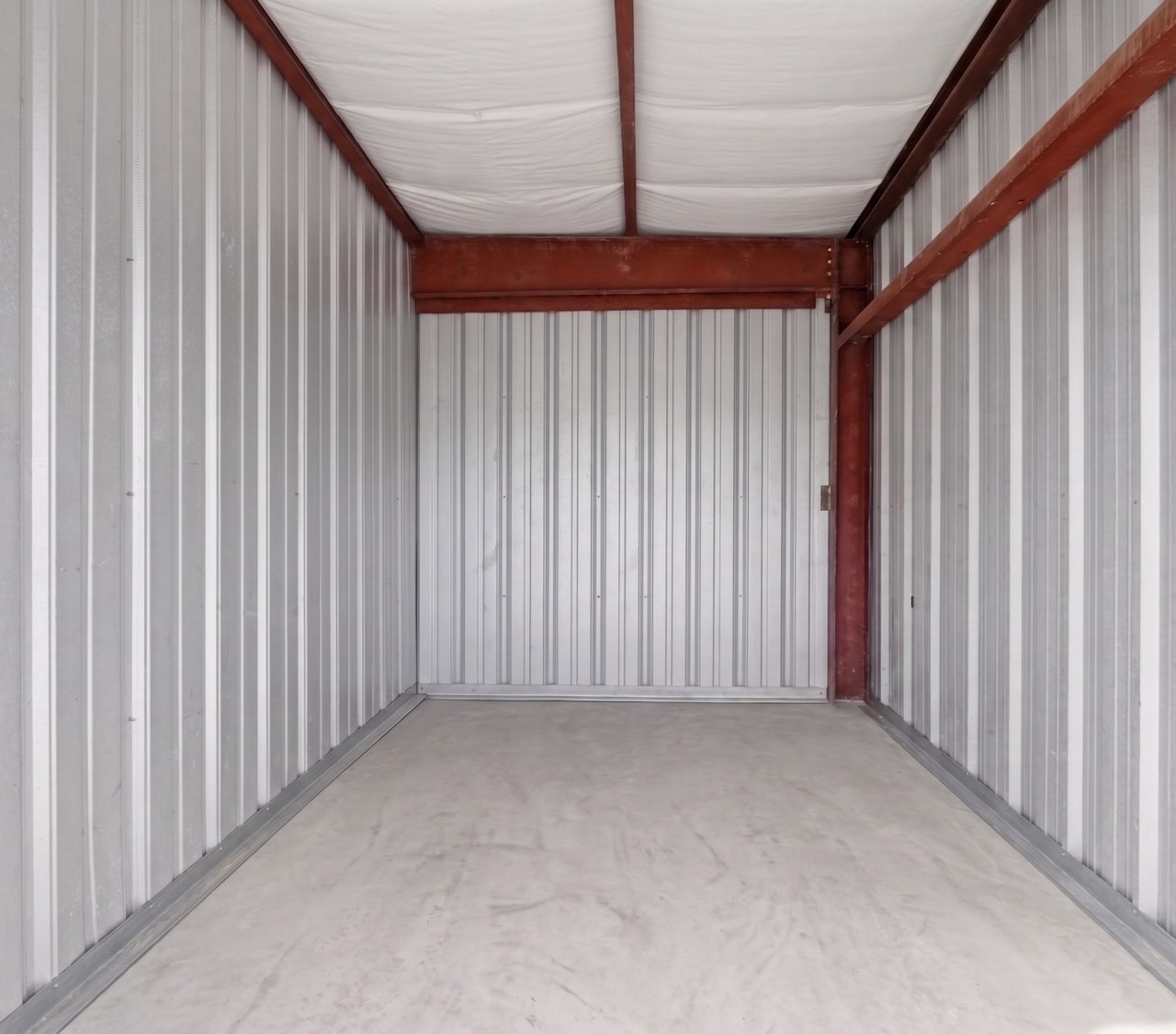 Empty storage unit interior with steel walls and concrete floor